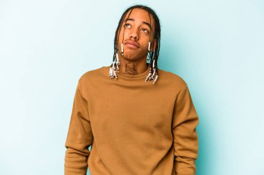 Genç Afrikalı Amerikalı adam mavi arka planda izole edilmiş hedeflerine ve amaçlarına ulaşma hayali kuruyor.