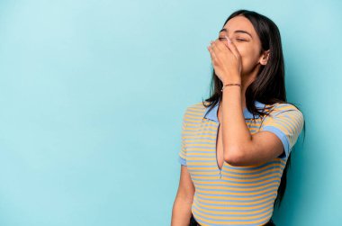 Genç İspanyol kadın mavi arka planda izole edilmiş gülerek, kaygısızca, doğal duygularla..