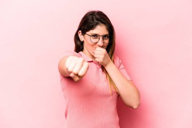 Pembe arka planda izole edilmiş genç beyaz kadın bir tartışma yüzünden yumruk, öfke, kavga ve boks atıyor..