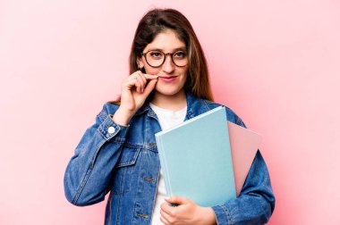 Pembe arka planda izole edilmiş genç beyaz kadın dudaklarında parmaklarıyla bir sır saklıyor..