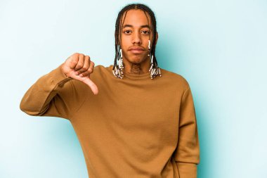 Genç Afro-Amerikan bir adam mavi arka planda izole edilmiş, hoşlanmadığı bir jest gösteriyor, başparmakları aşağıda. Anlaşmazlık konsepti.
