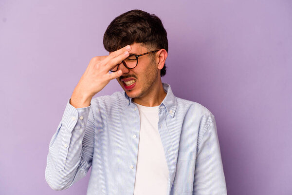 Young caucasian man isolated on purple background having a head ache, touching front of the face.