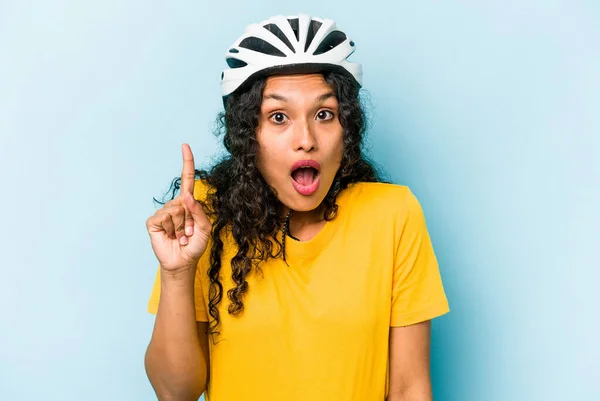青い背景に隔離されたヘルメットバイクを身に着けている若いヒスパニック系の女性はいくつかの素晴らしいアイデアを持っています 創造性の概念 — ストック写真