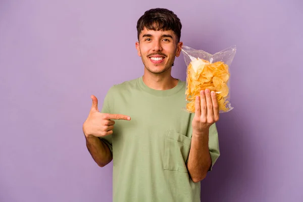 Jonge Spaanse Man Met Chips Geïsoleerd Paarse Achtergrond Persoon Wijzend — Stockfoto