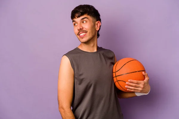 Młody Latynoski Koszykarz Człowiek Odizolowany Fioletowym Tle Patrzy Bok Uśmiechnięty — Zdjęcie stockowe