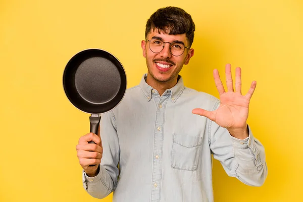 Joven Olla Hispana Sosteniendo Sartén Aislada Sobre Fondo Amarillo Sonriente — Foto de Stock