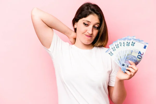 若い白人女性はピンクを背景にした紙幣を持ち 頭に触れ 選択をする — ストック写真