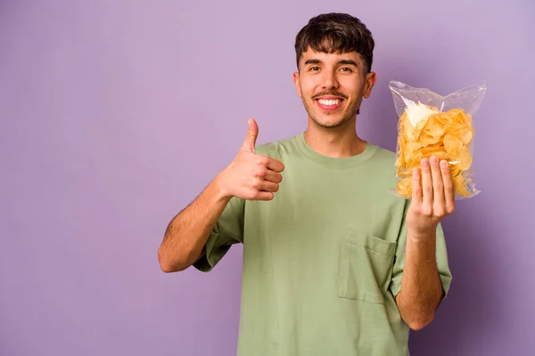 Jonge Latino Man Met Chips Geïsoleerd Paarse Achtergrond Glimlachen Het — Stockfoto