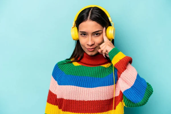 Young Hispanic Woman Listening Music Isolated Blue Background Pointing Temple — Stock Photo, Image