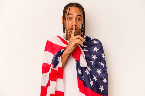 Young African American man holding a American flag isolated on white background keeping a secret or asking for silence.