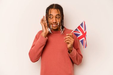 Beyaz arka planda izole edilmiş İngiliz bayrağı taşıyan genç Afrikalı Amerikalı bir adam bir dedikoduyu dinlemeye çalışıyor..