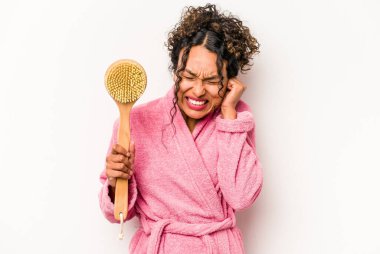 Sırt kaşıyıcısı tutan genç İspanyol kadın beyaz arka planda izole edilmiş kulakları elleriyle kapatıyor..