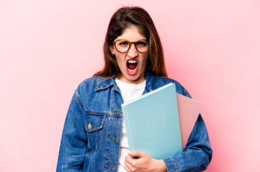 Pembe arka planda izole edilmiş genç beyaz kadın çok sinirli ve agresif bağırıyor..