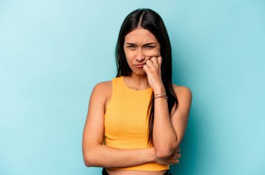 Genç İspanyol kadın mavi arka planda izole edilmiş düşünüyor, bakıyor, yansıtıyor, düşünüyor, hayal kuruyor..