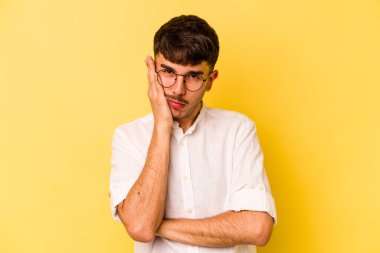 Sarı arka planda izole edilmiş genç beyaz adam sıkılmış, yorgun ve dinlenmeye ihtiyacı var..