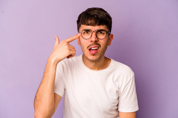Young caucasian man isolated on purple background showing a disappointment gesture with forefinger.