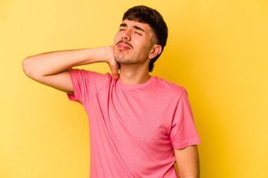 Genç beyaz adam sarı arka planda izole edilmiş dirsek masajı yapıyor, kötü bir hareketin ardından acı çekiyor..