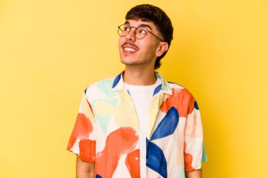 Sarı arka planda izole edilmiş genç beyaz adam gevşemiş ve mutlu gülüyor, boynunda dişlerini gösteriyor..