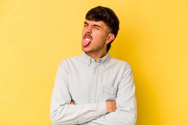 Sarı arka planda izole edilmiş beyaz bir genç. Komik ve dost canlısı bir dil uzatıyor..