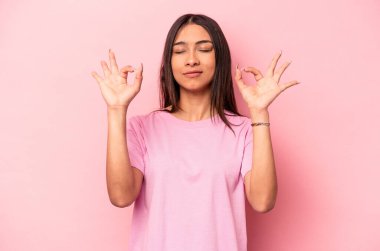 Pembe arka planda izole edilmiş genç İspanyol kadın sıkı çalışma gününden sonra rahatlıyor, yoga yapıyor..