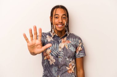 Beyaz arka planda izole edilmiş genç Afro-Amerikan adam gülümseyerek beş numarayı parmaklarıyla gösteriyor..