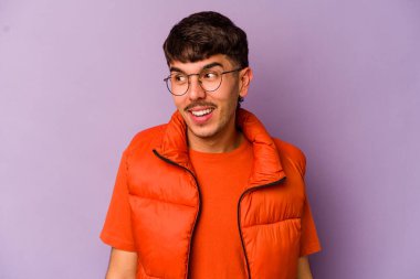 Mor arka planda izole edilmiş genç beyaz adam gülüyor ve gözlerini kapıyor, rahatlamış ve mutlu hissediyor..