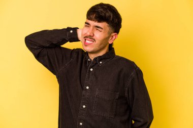 Sarı arka planda izole edilmiş genç beyaz adam yorgun ve uykulu bir şekilde ellerini başının üstünde tutuyor..