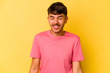 Sarı arka planda izole edilmiş genç beyaz adam gülüyor ve gözlerini kapıyor, rahatlamış ve mutlu hissediyor..