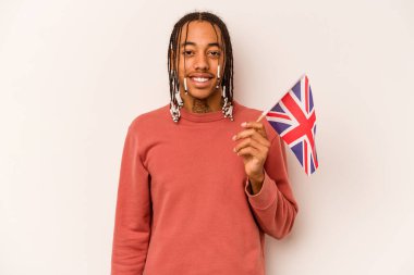 Beyaz arka planda izole edilmiş İngiliz bayrağı tutan genç Afrikalı Amerikalı adam mutlu, güler yüzlü ve neşeli..