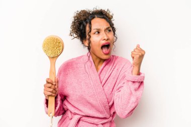 Beyaz arka planda izole edilmiş sırt kaşıyıcı tutan genç İspanyol kadın zaferden sonra yumruğunu kaldırıyor, kazanan konsept..