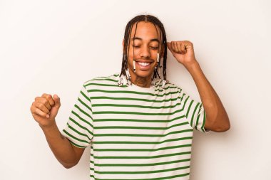 Beyaz arka planda izole edilmiş genç Afrikalı Amerikalı özel bir günü kutluyor, atlıyor ve enerjiyle kollarını kaldırıyor..