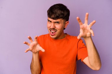 Mor arka planda izole edilmiş genç beyaz adam gergin ellerle çığlık atıyor..