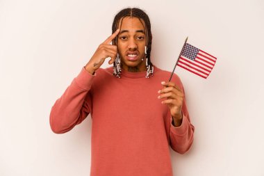 Beyaz arka planda izole edilmiş Amerikan bayrağı tutan genç Afrikalı Amerikalı adam işaret parmağıyla yaptığı hayal kırıklığı jestini gösteriyor..