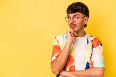 Sarı arka planda izole edilmiş genç beyaz adam rahatlamış bir şeyin fotokopi odasına baktığını düşünüyor..