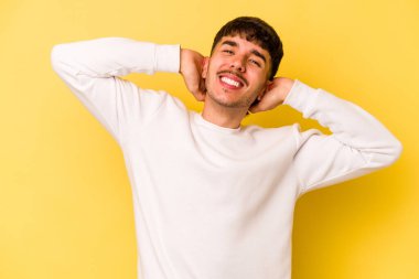 Sarı arka planda izole edilmiş, kollarını uzatan, rahat bir pozisyonda genç beyaz bir adam..