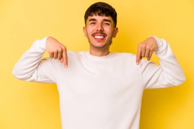 Sarı arka planda izole edilmiş genç beyaz adam parmakları aşağıda, olumlu bir his var..