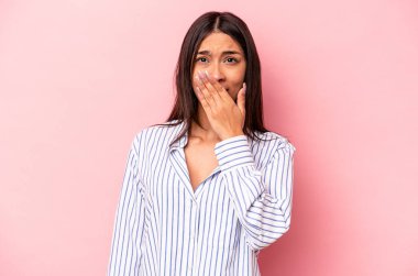 Pembe arka planda izole edilmiş genç İspanyol kadın şok olmuş, ağzı ellerle kaplanmış, yeni bir şey keşfetmeye hevesli..
