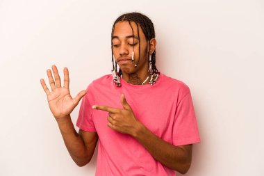 Beyaz arka planda izole edilmiş genç Afro-Amerikan adam gülümseyerek beş numarayı parmaklarıyla gösteriyor..