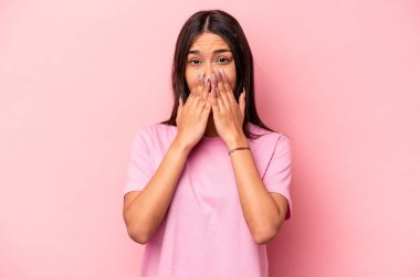 Pembe arka planda izole edilmiş genç İspanyol kadın şok olmuş, ağzı ellerle kaplanmış, yeni bir şey keşfetmeye hevesli..