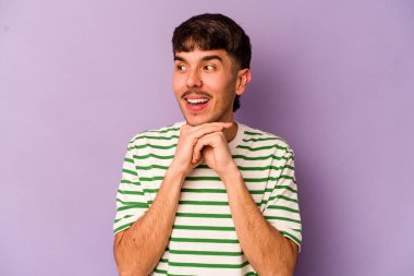 Kafkasyalı genç adam mor arka planda izole edilmiş şans diliyor, şaşırmış ve ağzı açık bir şekilde önüne bakıyor..