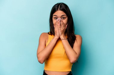 Mavi arka planda izole edilmiş genç İspanyol kadın elleri endişeli görünüyor..