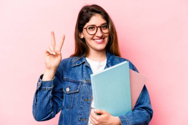 Pembe arka planda izole edilmiş genç beyaz kadın iki numarayı parmaklarıyla gösteriyor..