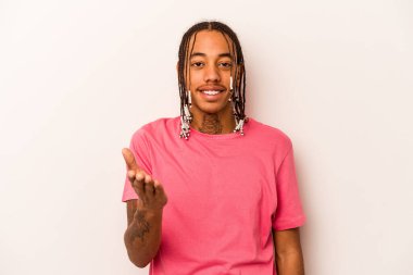 Beyaz arka planda izole edilmiş genç Afro-Amerikalı adam selamlaşma jesti olarak kameraya uzanıyor..