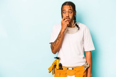 Mavi arka planda izole edilmiş genç Afrikalı Amerikalı bir adam rahatlamış fotokopi alanına bakan bir şey düşünüyor..
