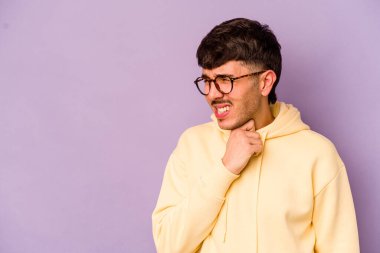 Kafkasyalı genç bir adam mor arka planda izole edilmiş kafasının arkasına dokunuyor, düşünüyor ve bir seçim yapıyor..