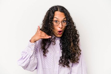 Beyaz arka planda izole edilmiş genç İspanyol kadın bir şeye gülüyor, elleriyle ağzını kapatıyor..