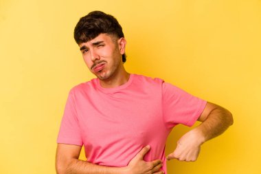 Sarı arka planda karaciğer ağrısı çeken, karnı ağrıyan genç beyaz bir adam..