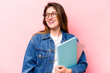 Pembe arka planda soyutlanmış genç beyaz kadın gülümseyen, neşeli ve keyifli görünüyor..