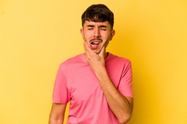 Sarı arka planda izole genç beyaz adam güçlü bir diş ağrısı, azıdişi ağrısı var..