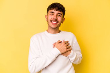 Sarı arka planda izole edilmiş beyaz bir genç, dost canlısı bir ifadeye sahip, avuçlarını göğsüne bastırıyor. Aşk konsepti.